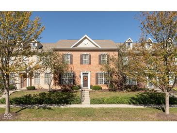 Charming brick townhome with well-maintained landscaping and inviting entrance with Autumn colored trees at 13504 E 131St St, Fishers, IN 46037