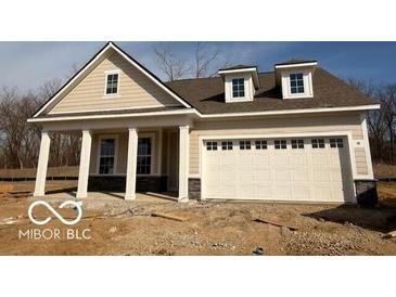 Charming single-story home featuring a two-car garage, covered porch, and light beige siding, nestled on a treed lot at 14383 Coyote Ridge Dr, Noblesville, IN 46060