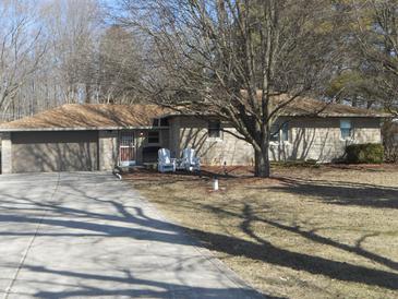 Charming single-story home with stone exterior, mature trees, and a cozy front yard with seating at 10128 E Troy Ave, Indianapolis, IN 46239