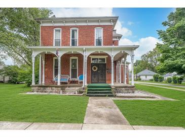 Charming two-story brick home featuring a spacious front porch and well-manicured lawn at 300 S Market St, Thorntown, IN 46071