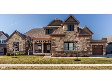 Charming exterior elevation with a stone and brick facade, covered porch, and well-manicured lawn at 4287 Prairie Falcon Dr, Zionsville, IN 46077
