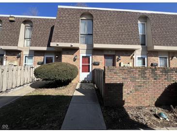 A charming townhome with a red brick facade, brown roofing, and well-maintained landscaping at 1344 Tishman Ln # 1344, Indianapolis, IN 46260