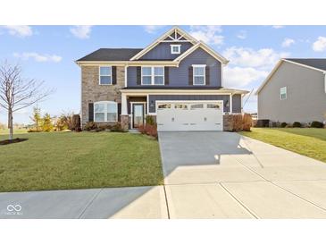 Charming two-story home featuring a stone and blue siding exterior and an attached two car garage at 13615 Moorcroft Dr, Fishers, IN 46037
