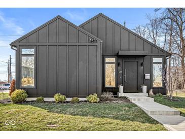 Modern home featuring dark vertical siding, a concrete walkway, and a well-manicured lawn at 1510 Columbia Ave, Indianapolis, IN 46202