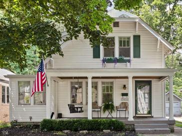 Charming two-story home featuring a covered front porch, swing, and an American flag at 5426 Broadway St, Indianapolis, IN 46220