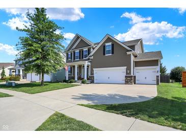 Inviting two-story home showcasing a three-car garage, manicured lawn, and tasteful architectural details at 7710 Eagle Crescent Dr, Zionsville, IN 46077