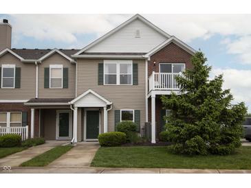 Charming townhouse with tan siding, brick accents, green trim, a small balcony, and a well-manicured lawn at 12145 Bubbling Brook Dr # 600, Fishers, IN 46038
