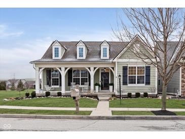 Charming single-Gathering home with a covered porch and swing, complemented by lush landscaping and a welcoming entrance at 15104 Midland Ln, Noblesville, IN 46062