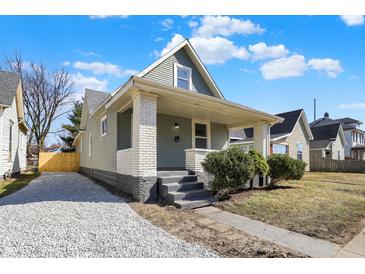 Charming home with light siding, white brick accents, covered porch, and gravel driveway at 39 S Holmes Ave, Indianapolis, IN 46222