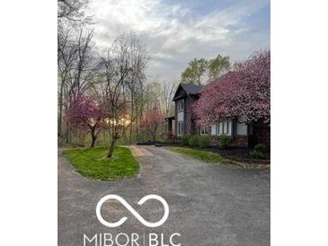Charming home exterior with a long driveway and beautiful pink trees in a landscaped yard at 4031 N Banta Rd, Bargersville, IN 46106