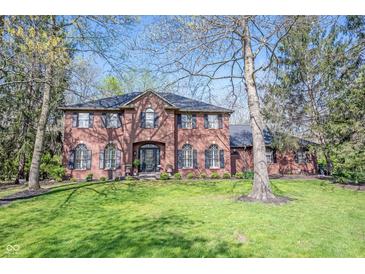 Stately brick home featuring a manicured lawn and professional landscaping at 8220 Traders Hollow Ct, Indianapolis, IN 46278