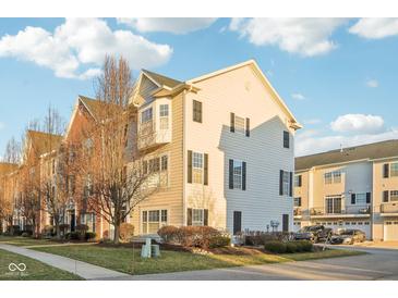 Attractive townhome with a combination of light beige siding, brick accents, and well-maintained landscaping at 8233 Katrina Way, Fishers, IN 46038