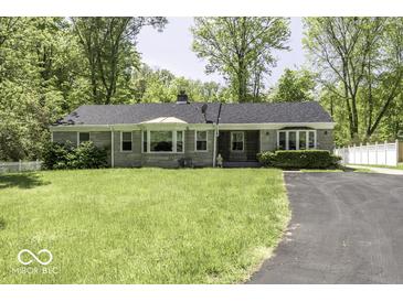 Charming single-story home featuring stone accents, a well-manicured lawn, and a paved driveway surrounded by mature trees at 6204 S Madison Ave, Indianapolis, IN 46227