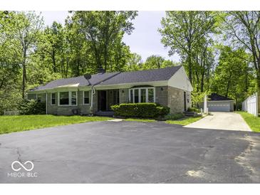 Charming single-story home featuring a stone facade, mature trees, and a spacious asphalt driveway at 6204 S Madison Ave, Indianapolis, IN 46227