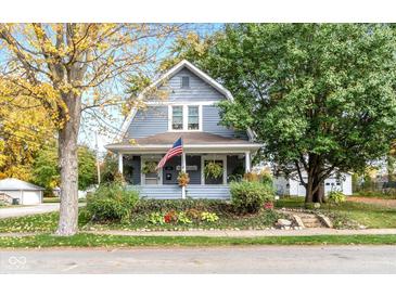 Charming two-story home featuring a welcoming front porch, mature trees, and a well-manicured lawn and garden at 117 N Leland St, Fortville, IN 46040
