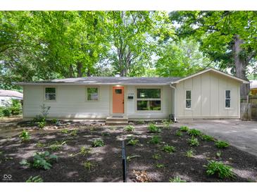 Charming ranch home with light-colored siding, a modern peach door, and a beautifully landscaped front yard at 1740 Haynes Ave, Indianapolis, IN 46240
