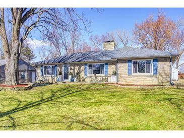 Charming stone-clad ranch home features a well-maintained lawn, blue shutters and mature shade trees at 7816 E St Joseph St, Indianapolis, IN 46219