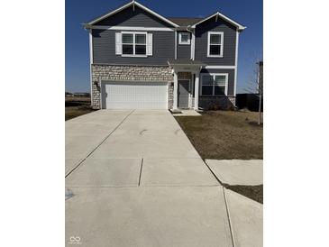 Two story home boasts vinyl siding, stone accents, two car garage, and a concrete driveway at 10950 N Heirloom Dr, Monrovia, IN 46157