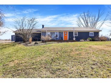 Charming single-story home with a cozy front porch and inviting orange door, surrounded by a well-maintained lawn at 15415 E 146Th St, Noblesville, IN 46060