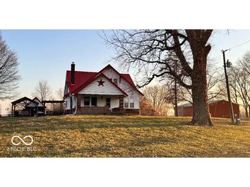 Charming farmhouse featuring a red roof, brick foundation, and a welcoming front porch at 8089 W Old State Road 67, Paragon, IN 46166