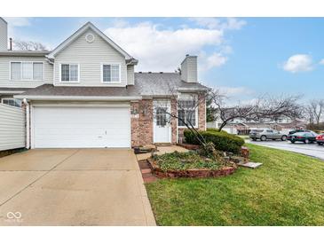 Charming townhome with a brick facade, attached garage, and well-maintained front lawn with garden beds at 915 Prestwick Dr # D, Indianapolis, IN 46214