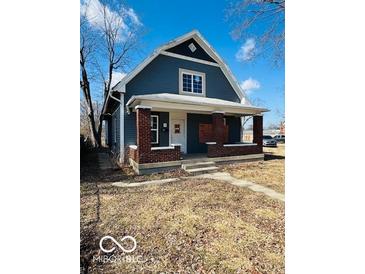 Charming blue two-story home featuring a covered front porch with brick columns at 1534 S State Ave, Indianapolis, IN 46203