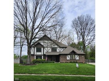 Charming Tudor-style home with brick facade, well-manicured lawn, and mature trees at 1728 Timber Heights Dr, Carmel, IN 46280