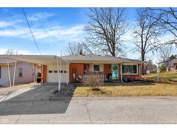 Charming brick home features a covered carport, landscaped front yard, and a bright blue front door at 230 N School St, Fortville, IN 46040