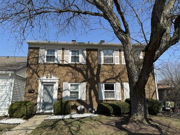 Charming townhouse featuring a brick facade, white shutters, and mature landscaping at 2826 Country Estates Dr, Indianapolis, IN 46227