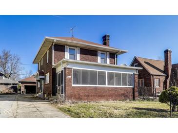Two story brick home featuring a covered porch and a well-maintained lawn at 518 Central S Ct, Indianapolis, IN 46205