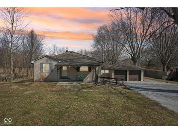 Charming single-story home featuring a covered porch and a detached two-car garage, set against a vibrant sunset sky at 4709 S County Road 500 E, Plainfield, IN 46168