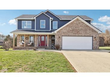 Charming two-story home features a brick and blue exterior, spacious front yard, and two-car garage at 12121 N Berling Dr, Mooresville, IN 46158