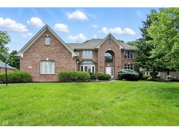Beautiful two-story brick home featuring manicured landscaping and a lush green lawn on a sunny day at 12307 Pebblepointe Pass, Carmel, IN 46033