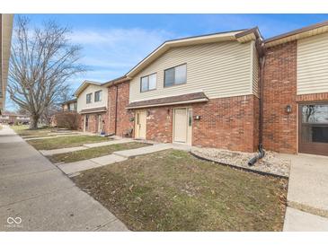 View of brick townhomes with siding, sidewalks, and small front yards under a clear blue sky at 8 Greenwood Trail S Dr, Greenwood, IN 46142