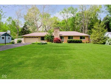 Charming ranch-style home with well-maintained lawn, stone chimney, and mature trees at 8808 Manderley Dr, Indianapolis, IN 46240