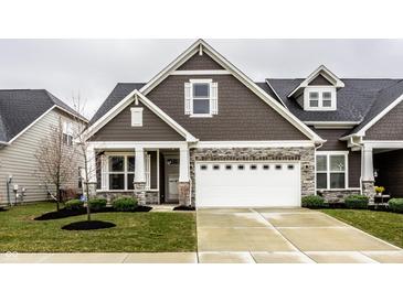 Charming home featuring brown siding, stone accents, a two-car garage and well-manicured lawn at 17099 Cole Evans Dr, Noblesville, IN 46060