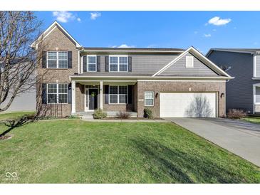 Charming two-story brick home with a well-manicured lawn and attached two-car garage on a sunny day at 281 Dovetree Dr, Danville, IN 46122