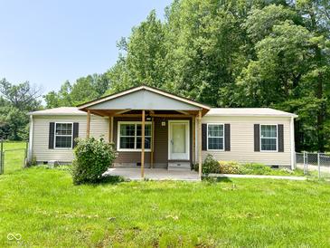 Charming single-story home featuring a covered porch, lawn, and mature trees in a peaceful, private setting at 5010 S 550 W, Columbus, IN 47201