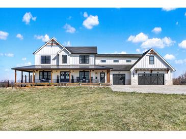 Charming two-story farmhouse with a covered porch, rocking chairs, and a two-car garage at 7418 W Old Sr 252, Edinburgh, IN 46124