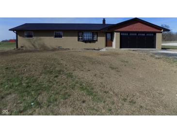 Charming single-story home with a black metal roof, two car garage and a spacious front yard at 10966 W State Road 142, Quincy, IN 47456