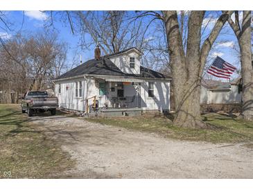 Charming one-story home with a welcoming front porch and American flag, set against a backdrop of mature trees at 3014 Alice Ave, Indianapolis, IN 46237