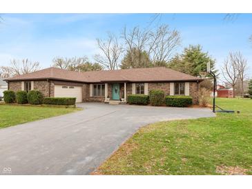 Charming brick ranch home featuring a spacious driveway, manicured landscaping, and a welcoming teal-colored front door at 3602 N County Road 950 E, Brownsburg, IN 46112