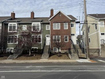 Three, two-story brick and painted-wood townhomes are featured in this exterior view at 614 E 11Th St, Indianapolis, IN 46202