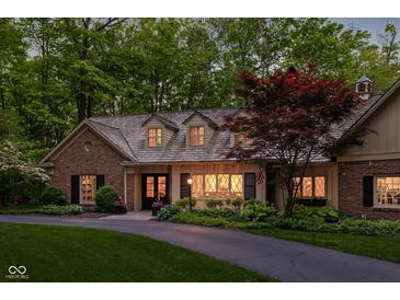Charming brick home with a well-manicured lawn, mature trees, and a welcoming driveway at 9080 Pickwick Dr, Indianapolis, IN 46260