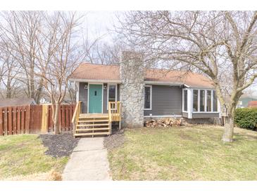 Charming one-story home featuring a stone chimney, teal front door, and wooden steps leading to the entrance at 953 S 5Th St, Noblesville, IN 46060