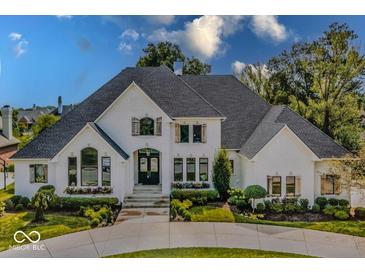 Stunning white home featuring lush landscaping, a circular drive, and beautiful architectural details at 10415 Charter Oaks, Carmel, IN 46032