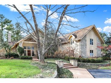 Charming stone and siding home with a beautiful landscaped front yard and walkway leading to the entrance at 10614 Winterwood, Carmel, IN 46032