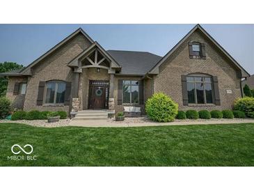 Charming brick home featuring a well-manicured lawn, professionally landscaped shrubbery, and a covered front porch at 1740 Golden Field Dr, Greenwood, IN 46143
