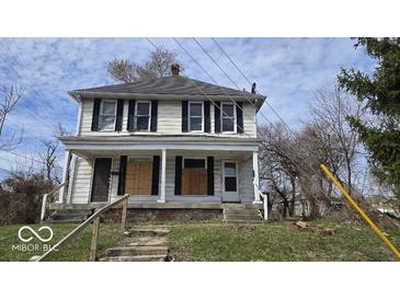 Two-story home with a covered porch, boarded windows, and some deferred maintenance at 18 N Sherman Dr, Indianapolis, IN 46201