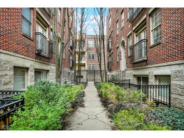 Attractive courtyard view of brick apartment buildings with a landscaped walkway and wrought iron gated entrance at 226 N Cleveland St # 226E, Indianapolis, IN 46204